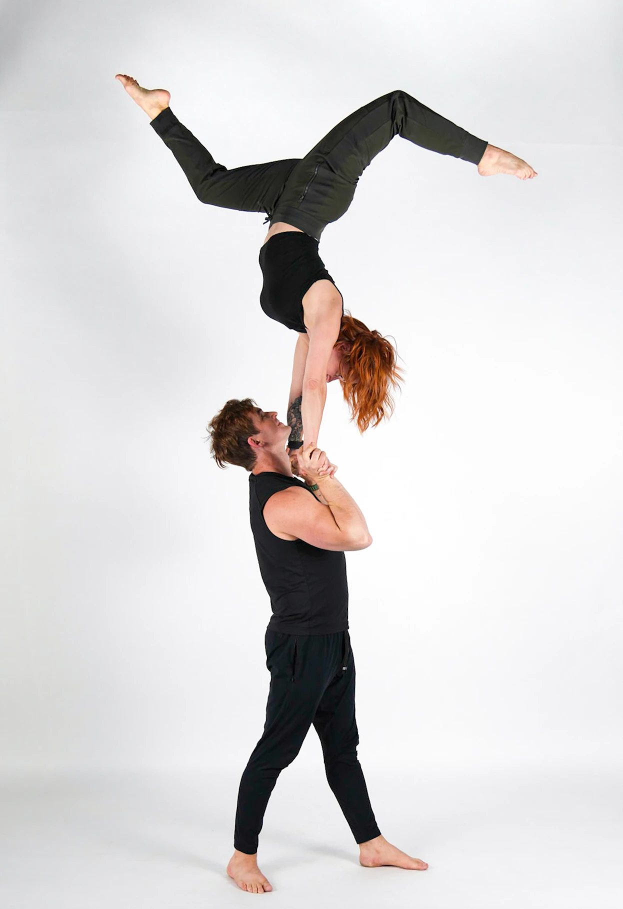 Jenny in a one-arm handstand balanced on Daniel's hands overhead
